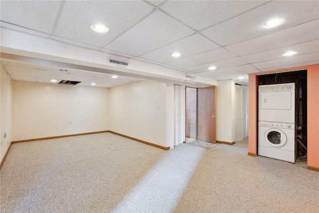 basement featuring stacked washing maching and dryer, light colored carpet, and a drop ceiling