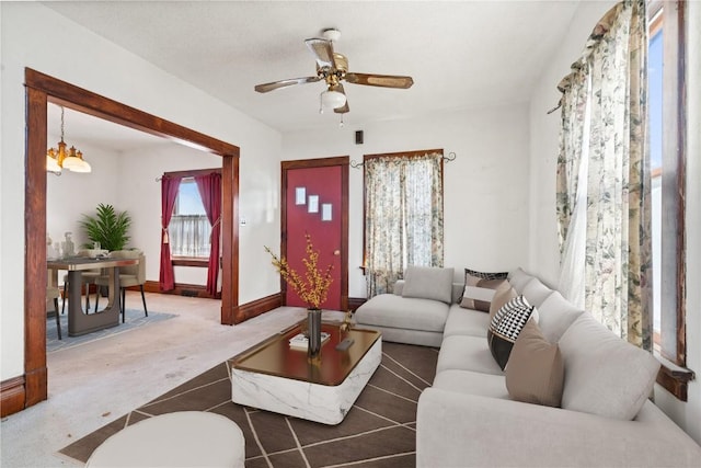 carpeted living room featuring ceiling fan with notable chandelier