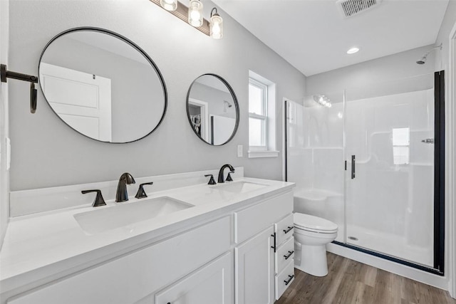 bathroom with vanity, toilet, wood-type flooring, and a shower with door