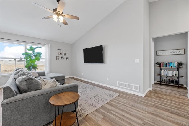 living room with ceiling fan, high vaulted ceiling, and light hardwood / wood-style flooring