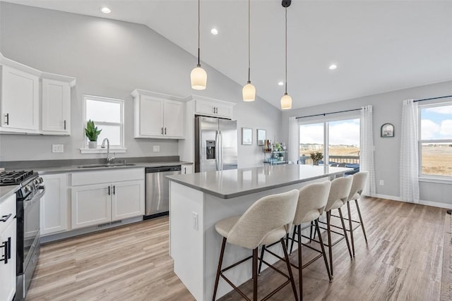 kitchen with sink, white cabinets, stainless steel appliances, and a kitchen island