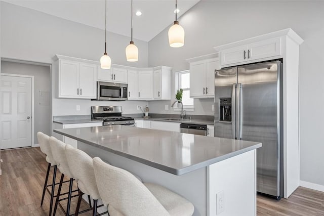 kitchen with pendant lighting, a kitchen island, sink, white cabinetry, and stainless steel appliances