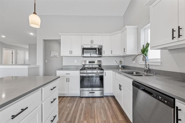 kitchen with sink, pendant lighting, stainless steel appliances, and white cabinetry