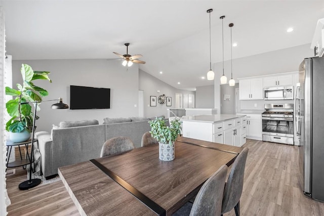 dining area featuring vaulted ceiling, ceiling fan, and light hardwood / wood-style flooring