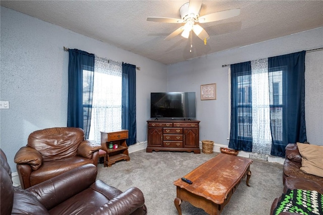 carpeted living room featuring ceiling fan and a textured ceiling