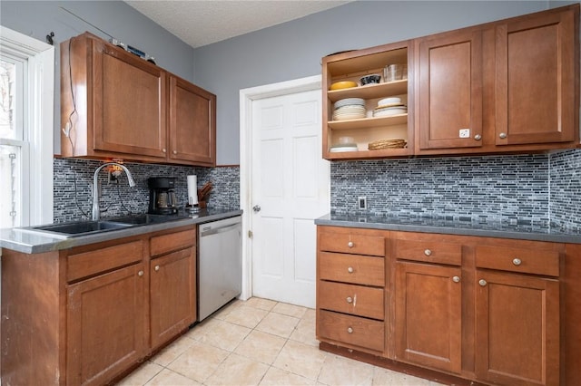 kitchen featuring a textured ceiling, stainless steel dishwasher, tasteful backsplash, sink, and light tile patterned floors