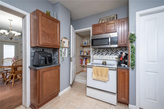 kitchen featuring a textured ceiling, white electric range oven, an inviting chandelier, tasteful backsplash, and light tile patterned floors