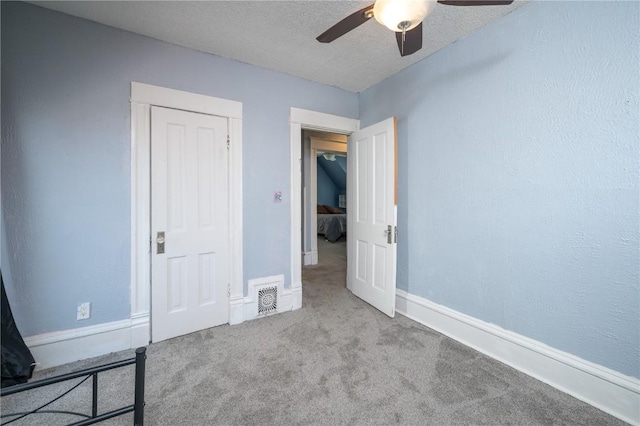 unfurnished bedroom featuring light carpet, ceiling fan, and a textured ceiling