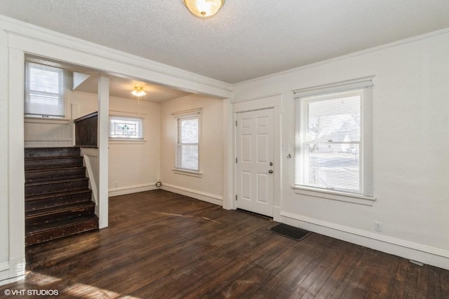 foyer entrance with dark wood-type flooring, a textured ceiling, and ornamental molding