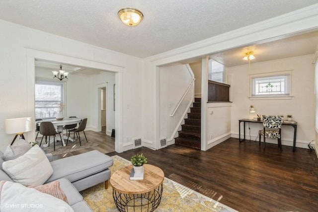 living area with a chandelier, stairway, visible vents, and wood finished floors