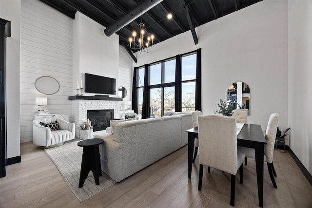 living room with arched walkways, a high ceiling, an inviting chandelier, a brick fireplace, and wood finished floors