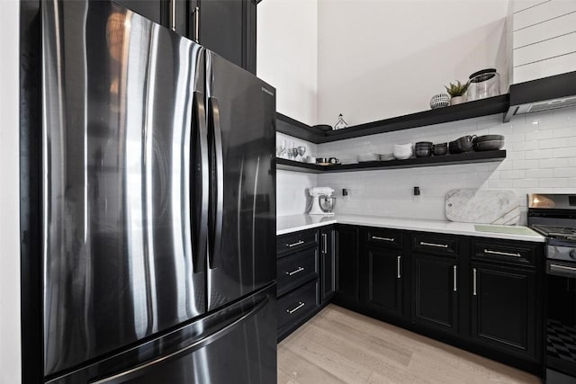 kitchen with range with gas cooktop, freestanding refrigerator, light countertops, dark cabinetry, and open shelves