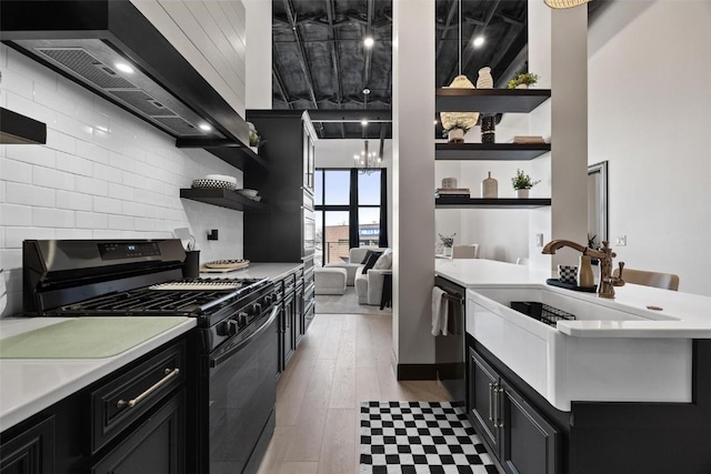 kitchen featuring light hardwood / wood-style floors, sink, custom range hood, black gas range oven, and dishwashing machine