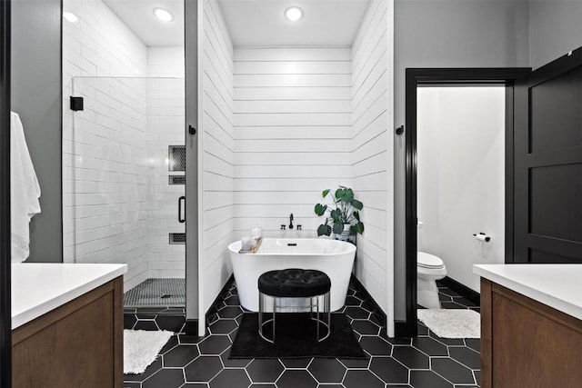 bathroom featuring a stall shower, toilet, tile patterned floors, vanity, and a freestanding tub