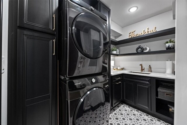 washroom with sink, stacked washer and clothes dryer, and cabinets