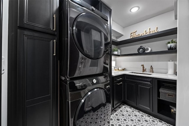 laundry area featuring cabinet space, a sink, stacked washing maching and dryer, and light tile patterned floors