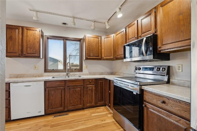 kitchen with light wood-type flooring, appliances with stainless steel finishes, and sink