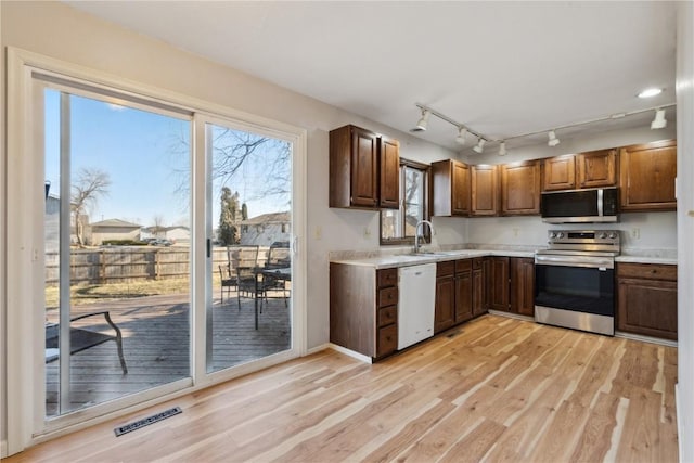 kitchen with appliances with stainless steel finishes, light hardwood / wood-style flooring, and sink