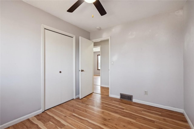 unfurnished bedroom featuring light wood-type flooring, ceiling fan, and a closet