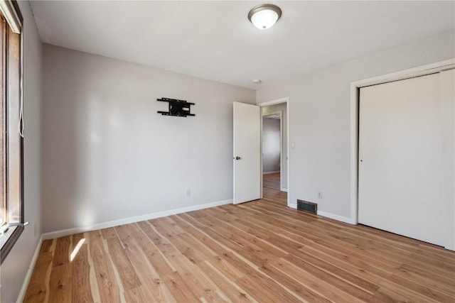 unfurnished bedroom with light wood-type flooring and a closet