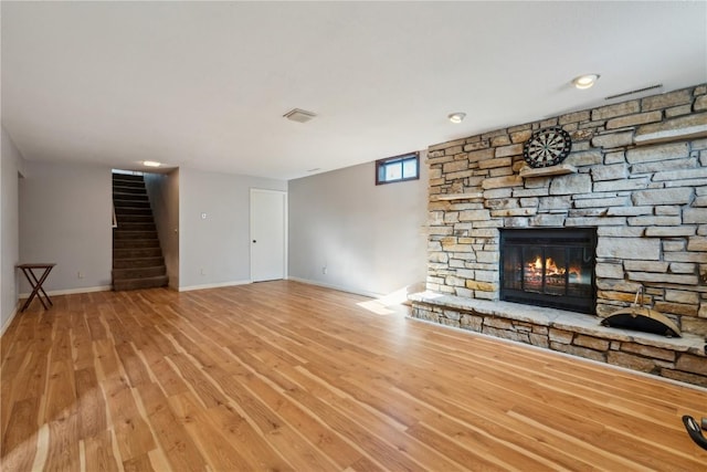 unfurnished living room featuring light hardwood / wood-style floors and a stone fireplace