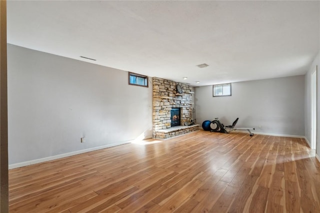 unfurnished living room featuring light hardwood / wood-style flooring and a stone fireplace