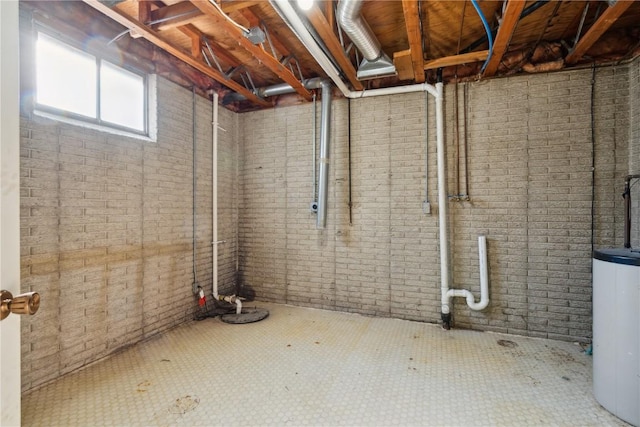 basement featuring water heater and brick wall