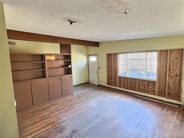 unfurnished living room featuring a textured ceiling and hardwood / wood-style floors