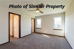 unfurnished bedroom with ceiling fan, multiple windows, and dark carpet