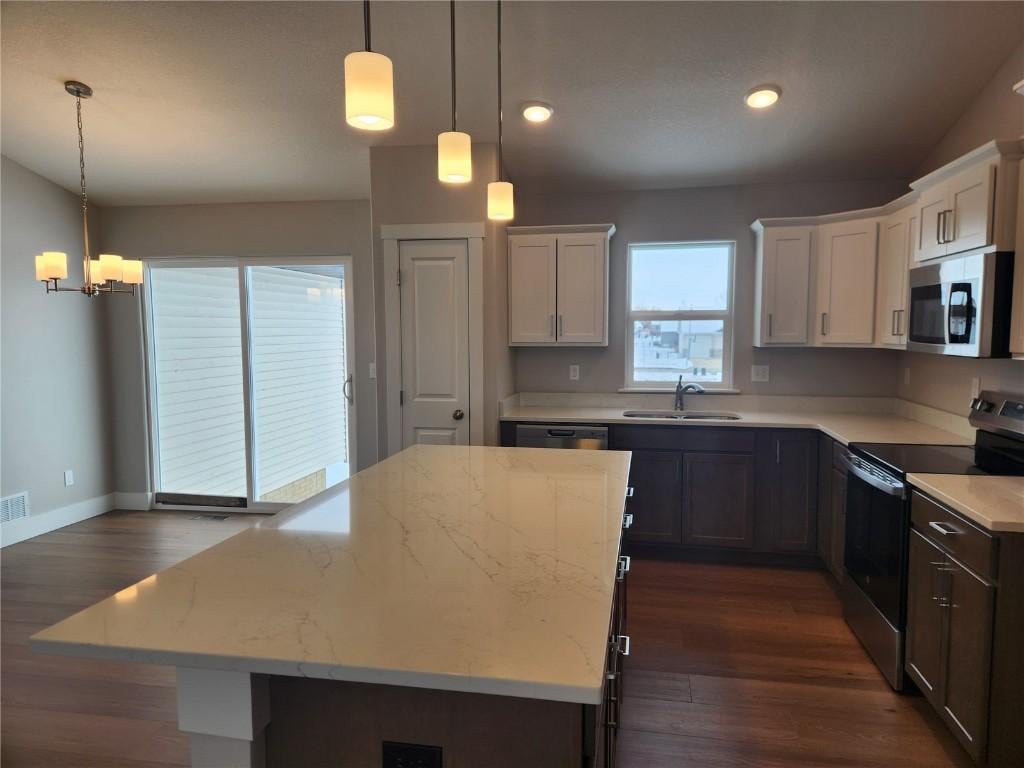 kitchen featuring dark wood finished floors, light stone counters, appliances with stainless steel finishes, and a sink