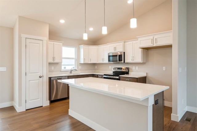 6188 Cope Dr, Marion, IA 52302 - kitchen featuring appliances with stainless steel finishes, a sink, a center island, wood finished floors, and white cabinetry