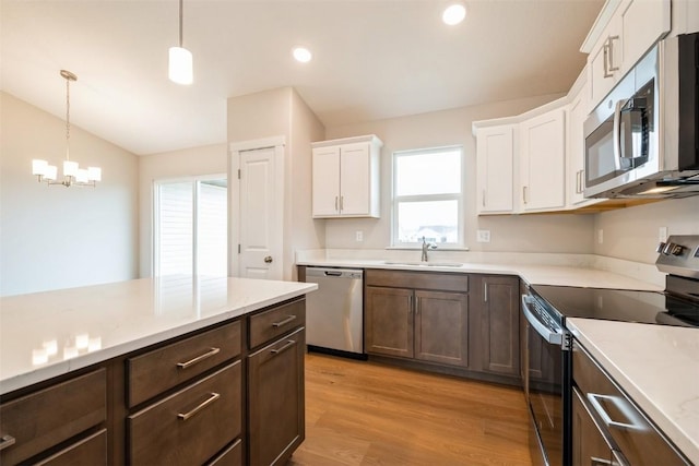 6188 Cope Dr, Marion, IA 52302 - kitchen with appliances with stainless steel finishes, a sink, white cabinetry, light wood-style flooring, and decorative light fixtures
