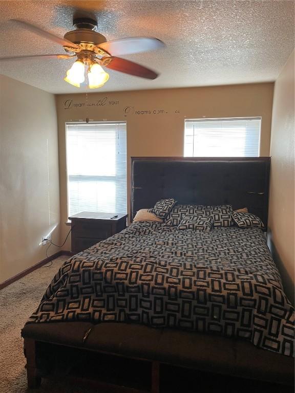 bedroom with a textured ceiling, carpet floors, and ceiling fan