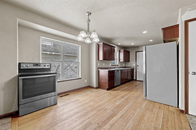 kitchen with stainless steel appliances, an inviting chandelier, pendant lighting, and light hardwood / wood-style floors