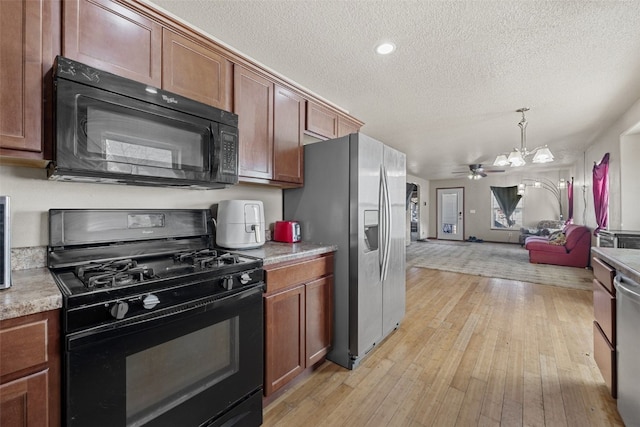 kitchen with decorative light fixtures, light hardwood / wood-style floors, black appliances, a textured ceiling, and an inviting chandelier