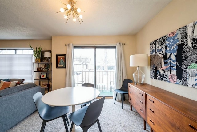 carpeted dining room featuring a textured ceiling and a chandelier