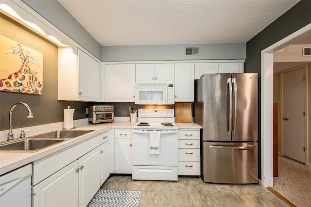 kitchen featuring sink, white appliances, white cabinets, and a textured ceiling