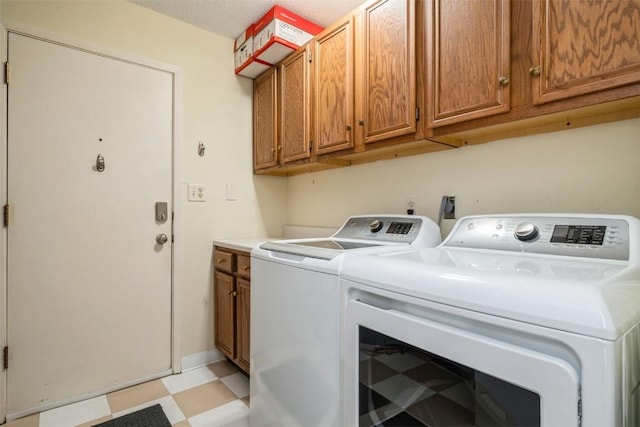 laundry room featuring cabinets, a textured ceiling, and washing machine and dryer