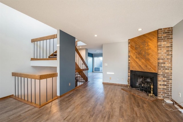 unfurnished living room with wood-type flooring, a fireplace, and wooden walls