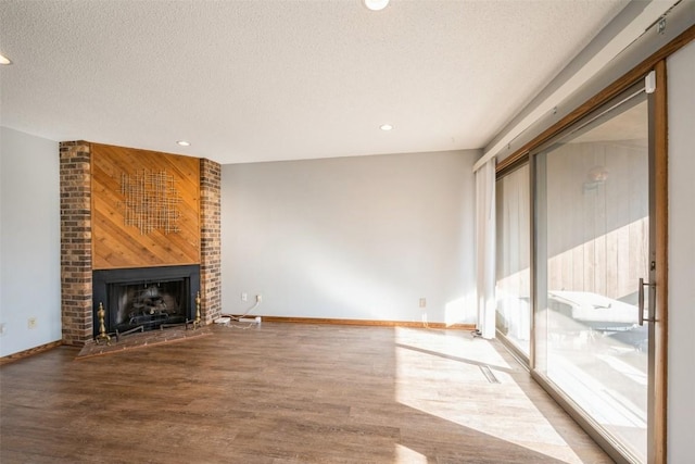 unfurnished living room featuring hardwood / wood-style flooring, a large fireplace, and a textured ceiling