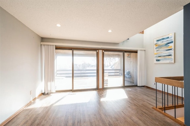 interior space with a wealth of natural light, a textured ceiling, and hardwood / wood-style flooring