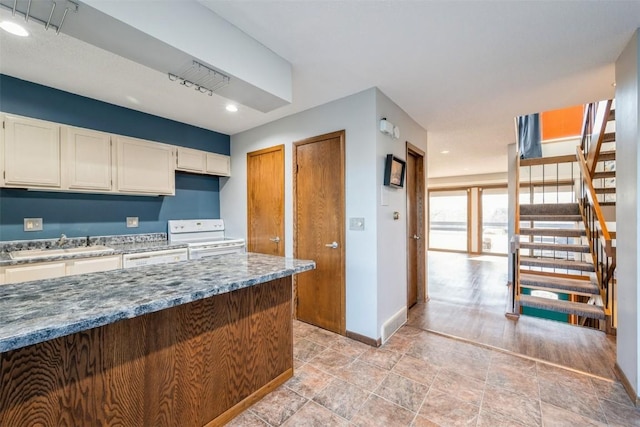 kitchen with sink, white range with electric cooktop, and dark stone counters