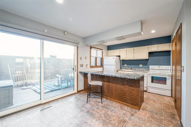 kitchen featuring a kitchen bar, light stone countertops, white appliances, and sink