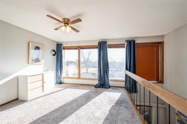 interior space with light carpet, ceiling fan, and a textured ceiling