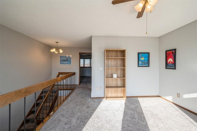 carpeted spare room with ceiling fan with notable chandelier, a textured ceiling, and built in features