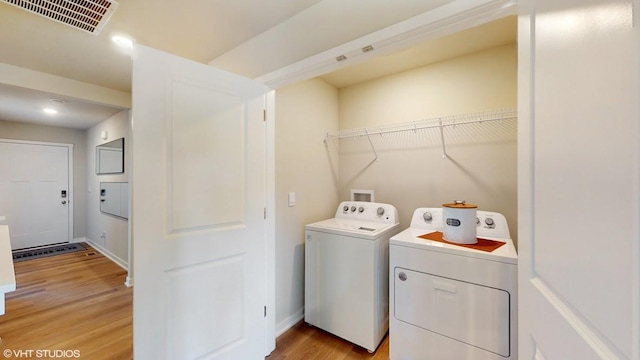 laundry area featuring washer and clothes dryer and light hardwood / wood-style floors