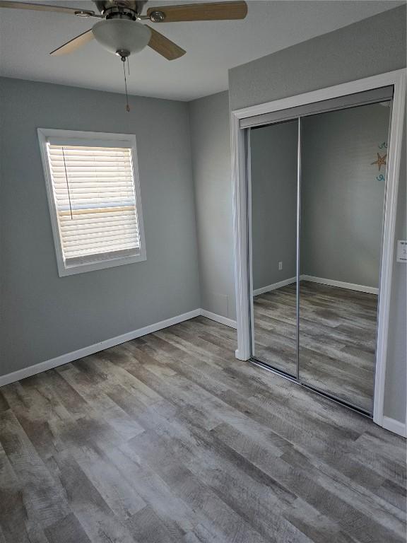 unfurnished bedroom featuring ceiling fan, a closet, and wood-type flooring