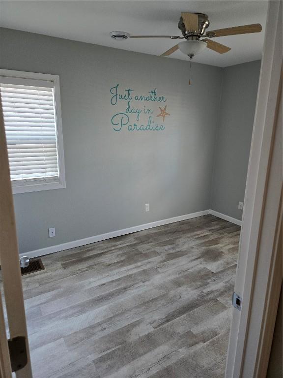 empty room with ceiling fan and light hardwood / wood-style flooring