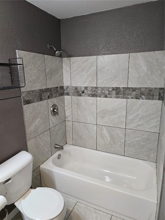 bathroom with toilet and tiled shower / bath