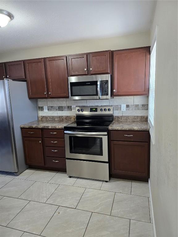 kitchen featuring decorative backsplash, light tile patterned floors, and appliances with stainless steel finishes